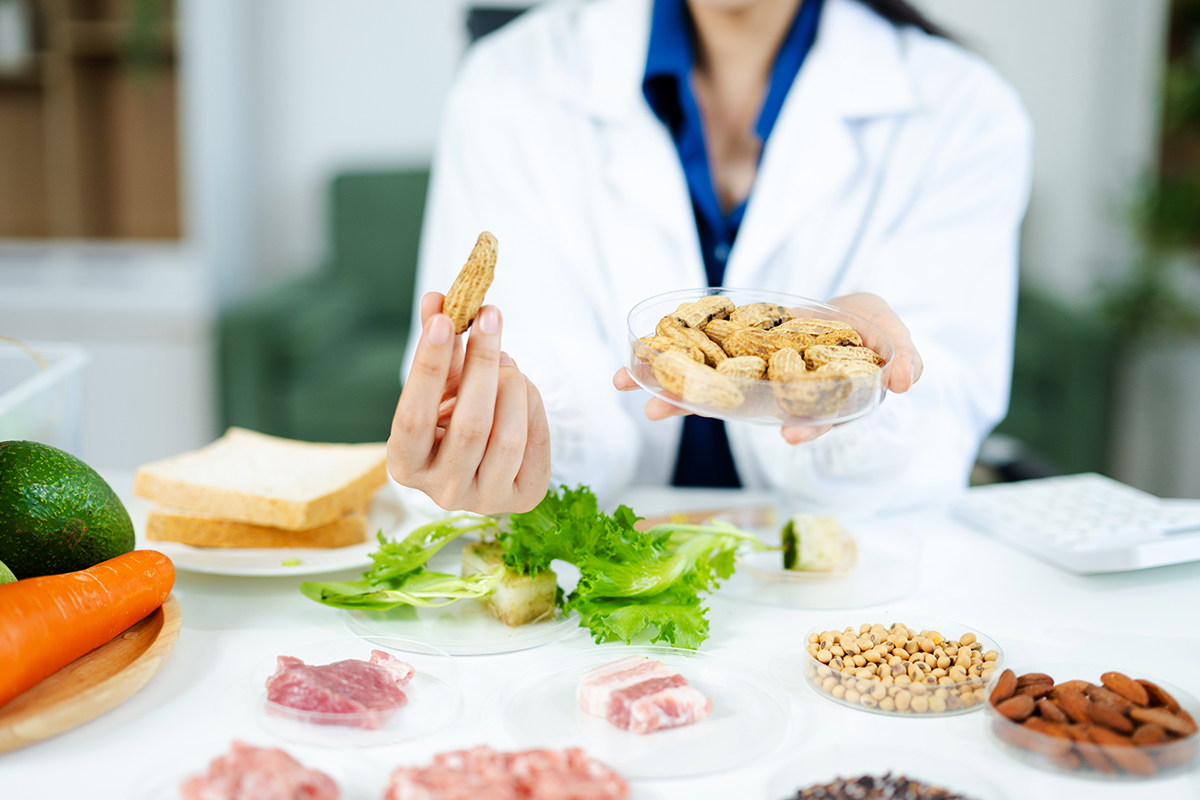 Nutrition expert in lab coat presenting soybeans and almonds in petri dishes