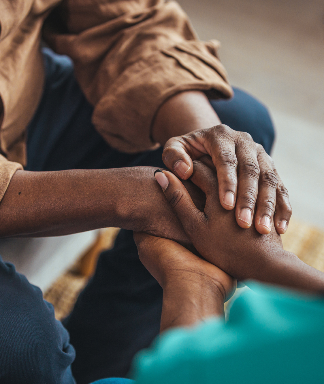 Close-up of two people holding hands, offering comfort and support