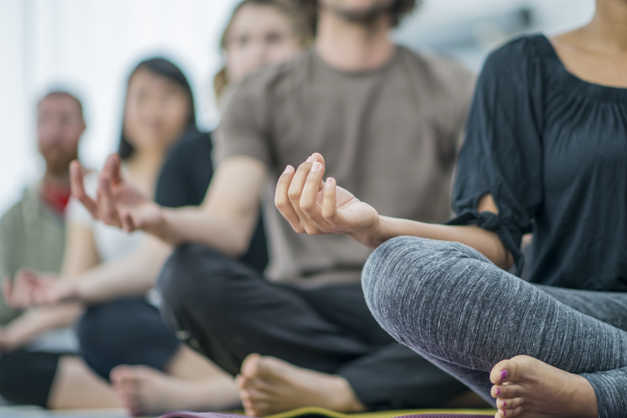 individuals sitting cross legged in row meditating