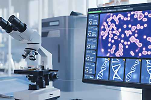 microscope beside a computer screen showing dna strands
