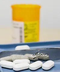 several pills with a prescription bottle in the background